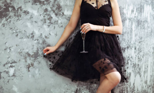 Smiling woman in black dress with a glass of champagne. close up. party concept